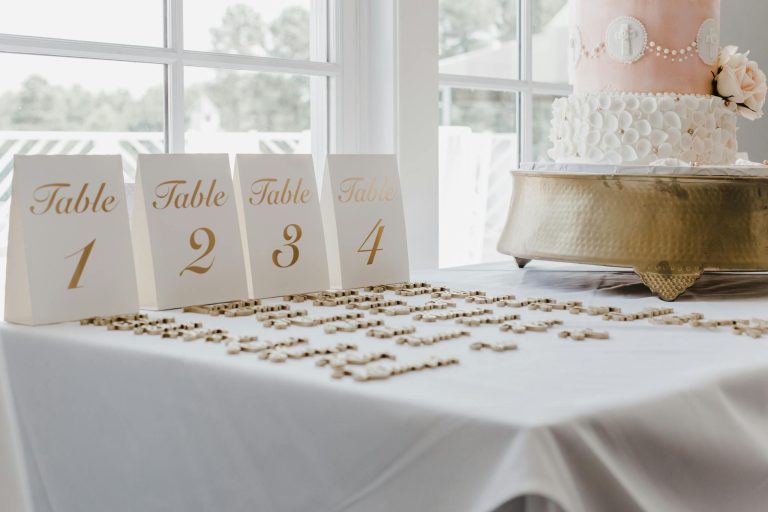 A beautifully set wedding reception table with numbers and an elegant cake, perfect for a classic wedding theme.