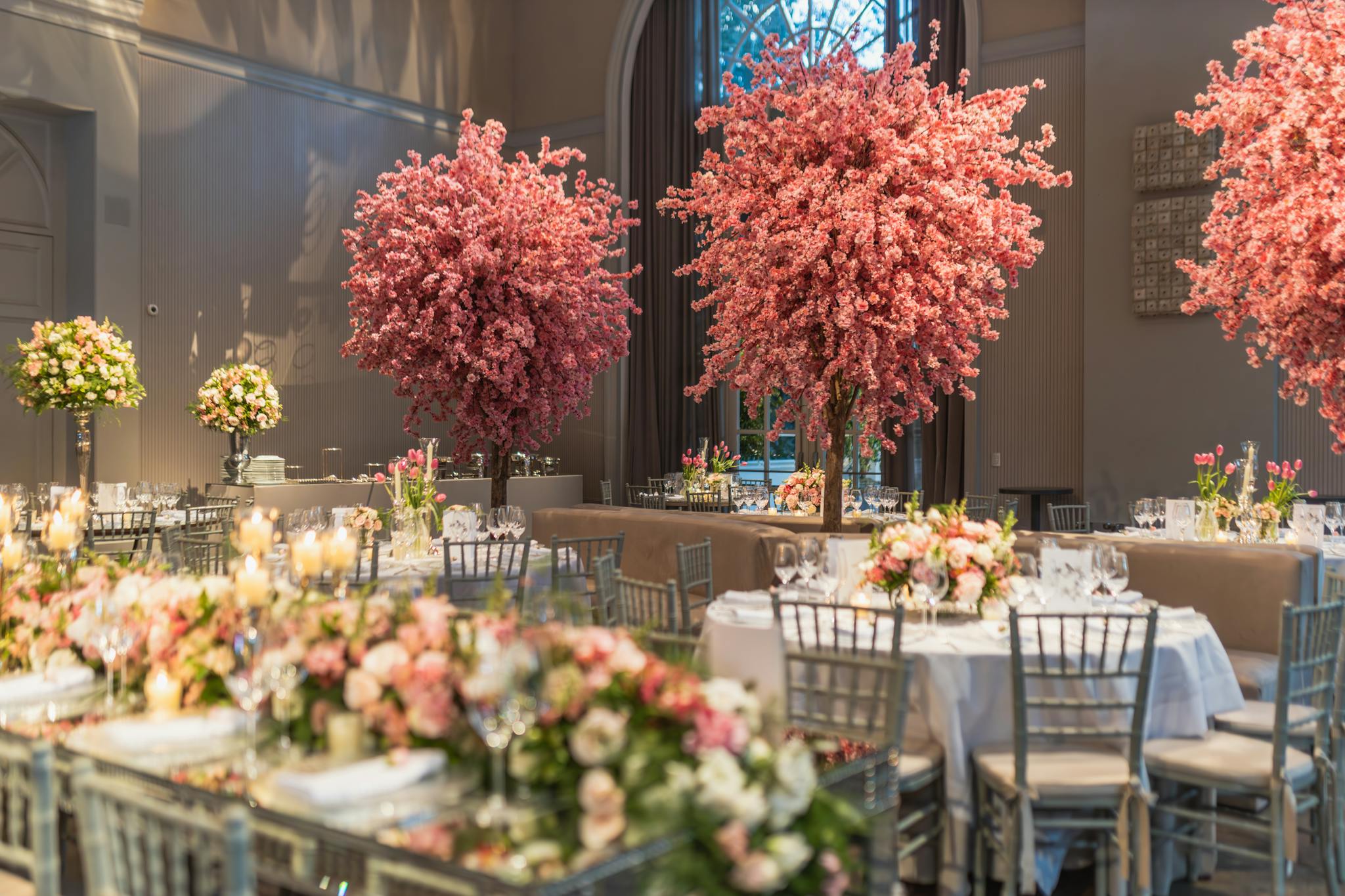 Stunning wedding reception with cherry blossom decor and elegantly set tables in a luxurious venue.
